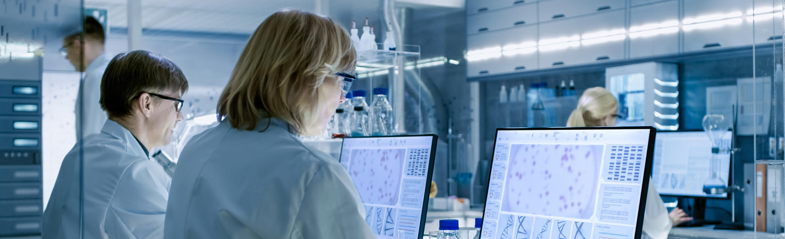 Female and Male Scientists Working on their Computers In Big Modern Laboratory